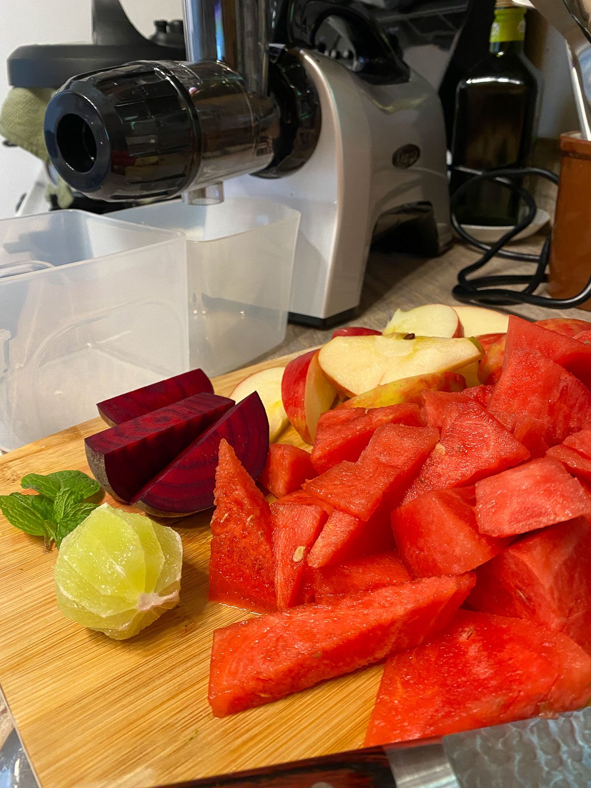 cut and peel ingredients for Fresh Watermelon Juice Blend alongside a juicer