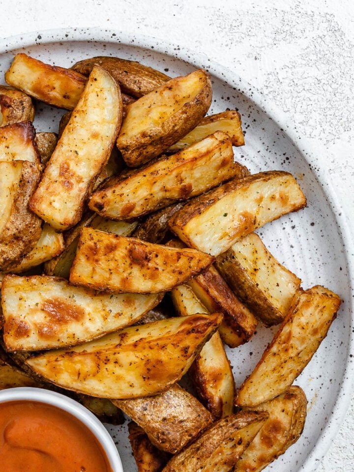 completed Air Fryer Potato Wedges plated on a white plate alongside a sauce