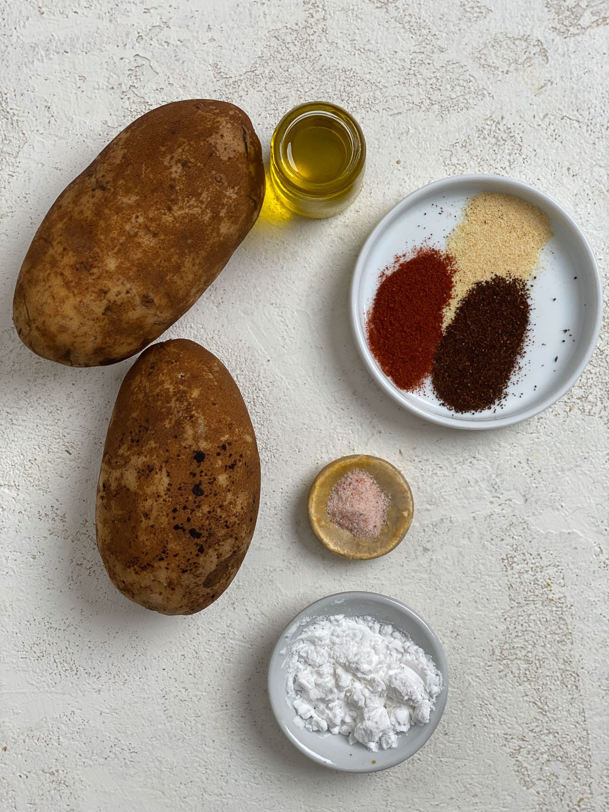 ingredients for air fryer potato wedges against a white surface