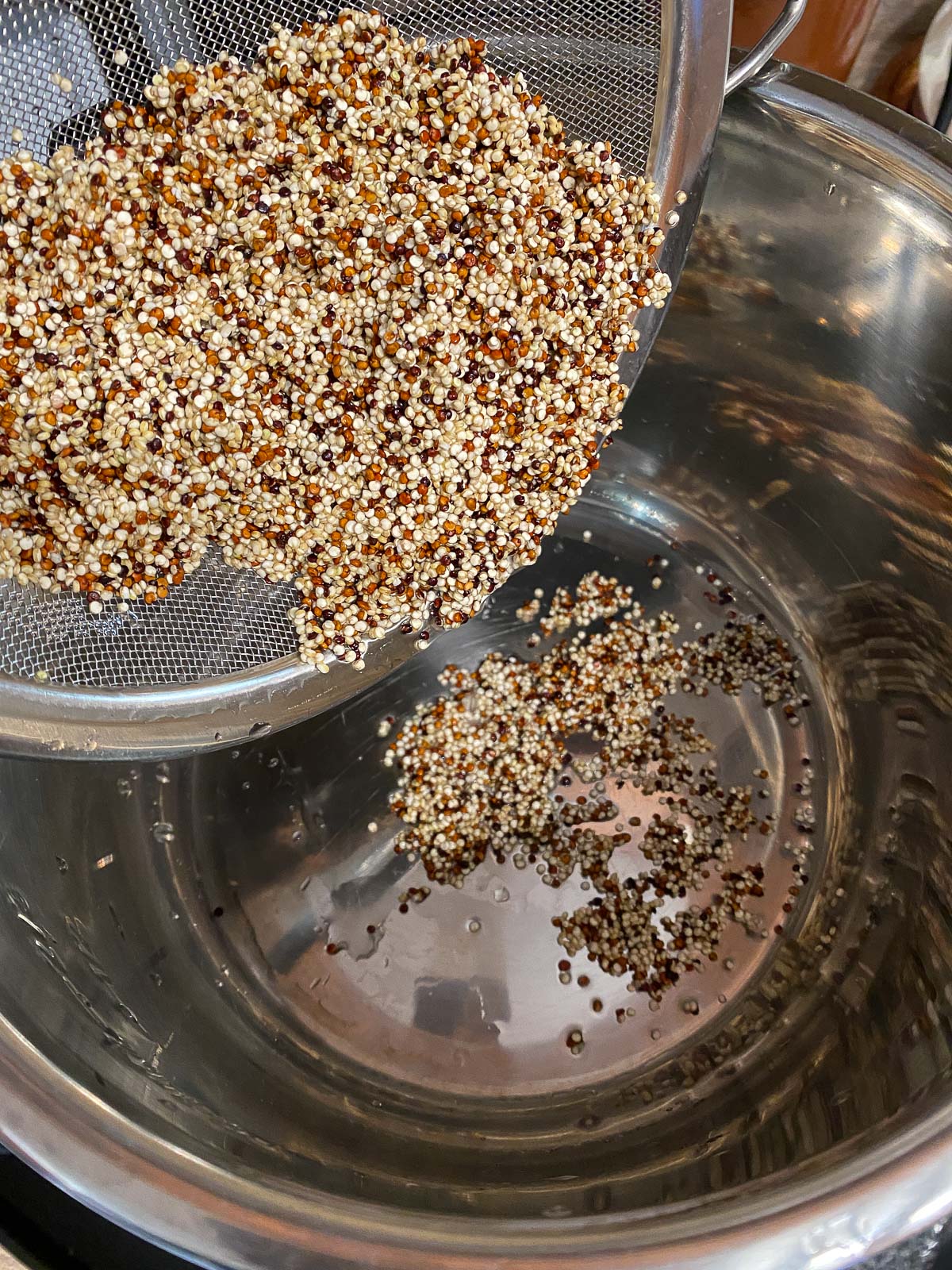 process shot of quinoa being poured into a stainless steel bowl