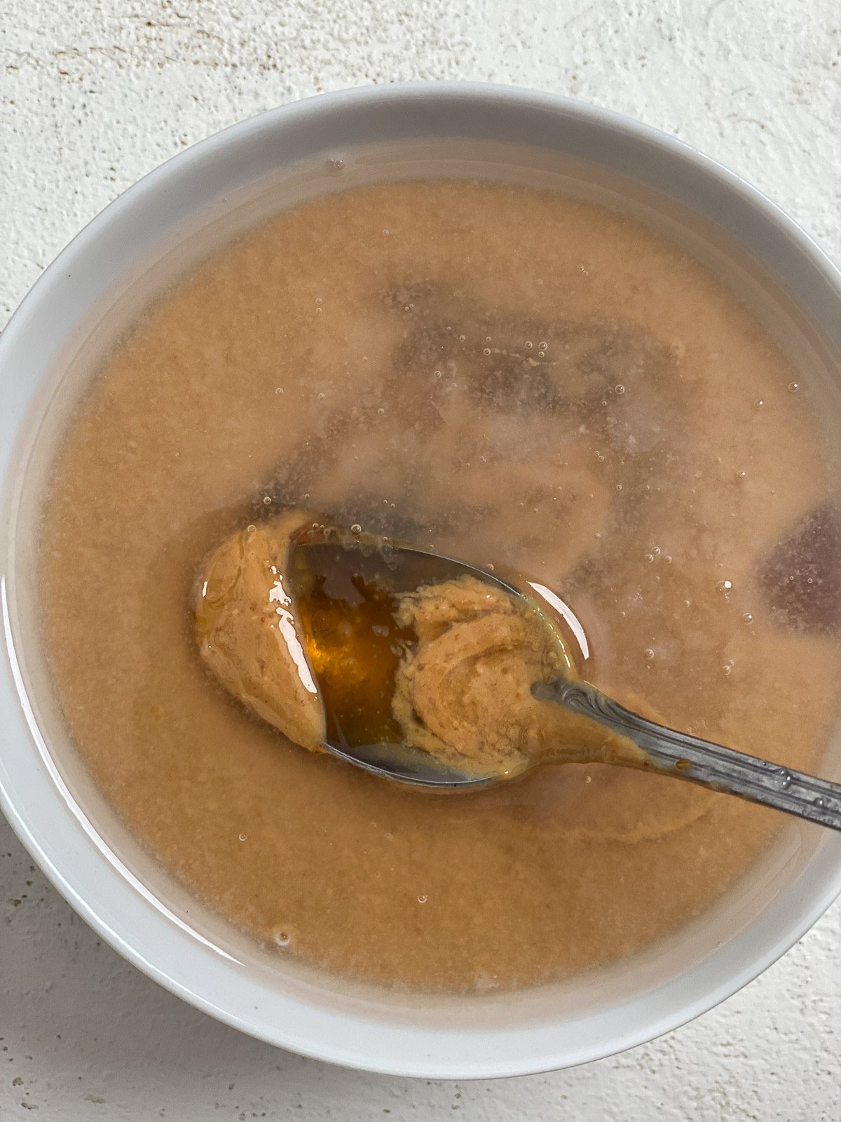 process of mixing ingredients for Simple Vegan Caramel in a white bowl