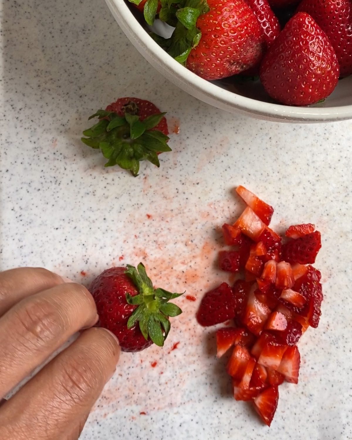 process of cutting strawberries on a white surface