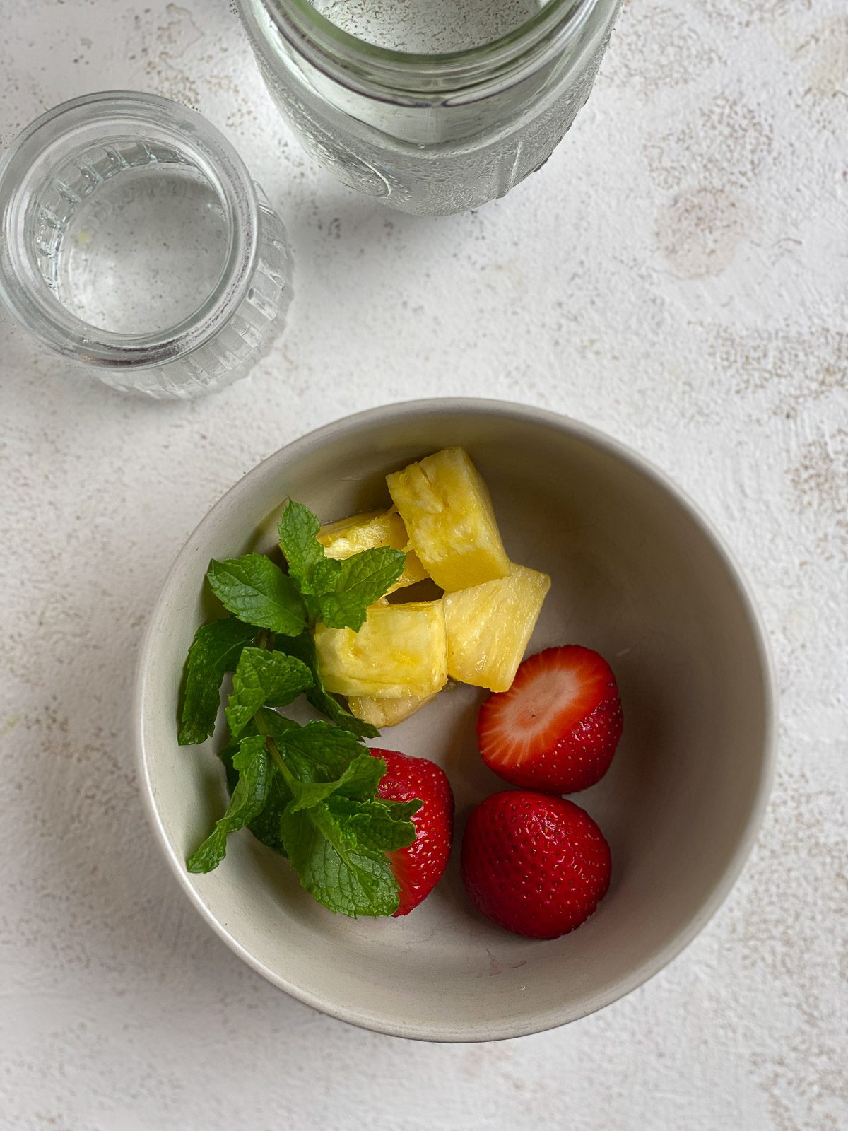 ingredients for Strawberry Pineapple Mocktail in a bowl on a white surface
