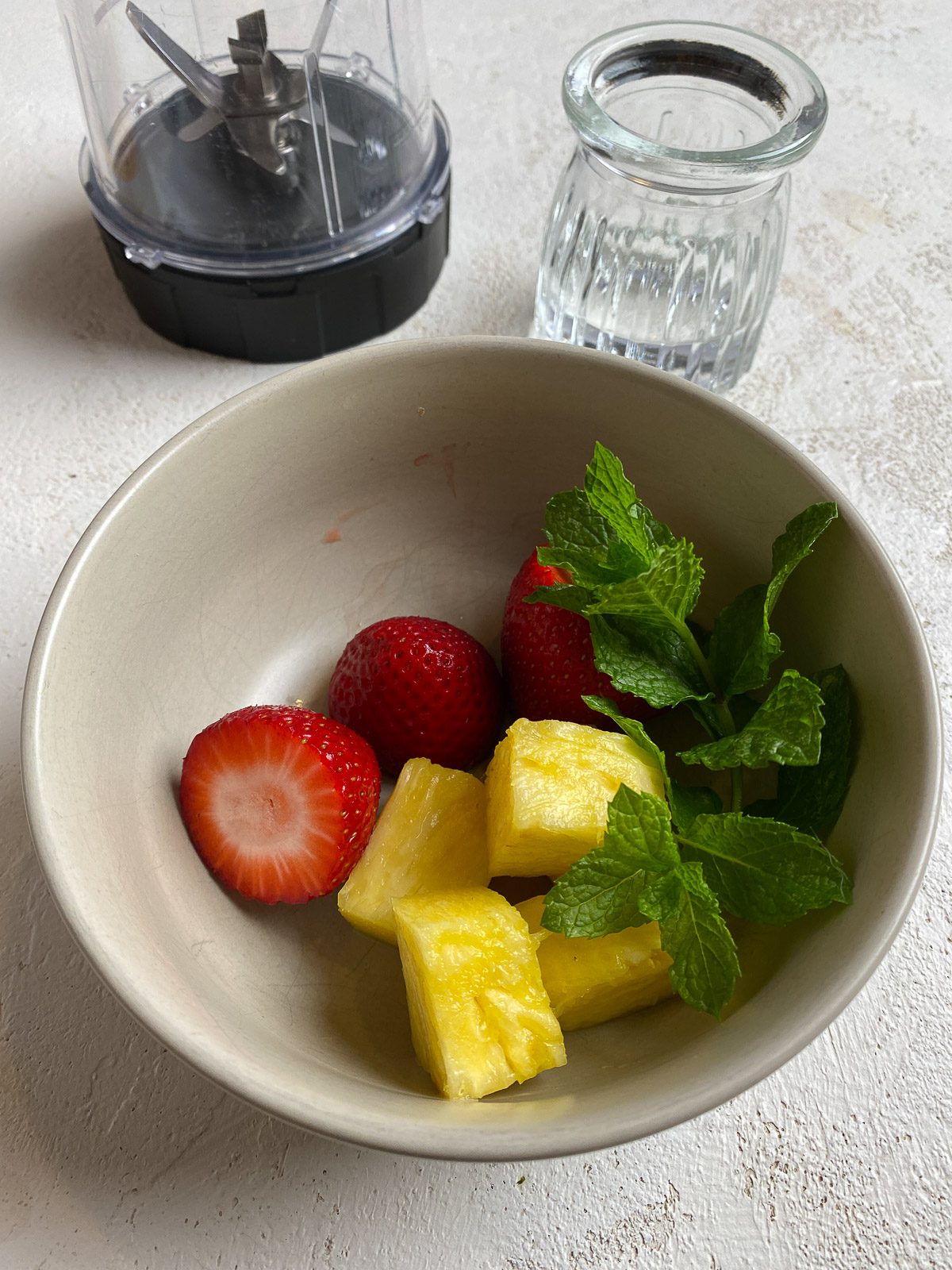 ingredients for Strawberry Pineapple Mocktail in a bowl on a white surface