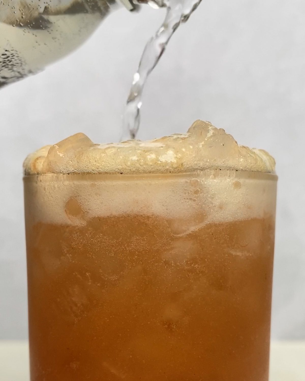 process of pouring Strawberry Pineapple Mocktail into glass