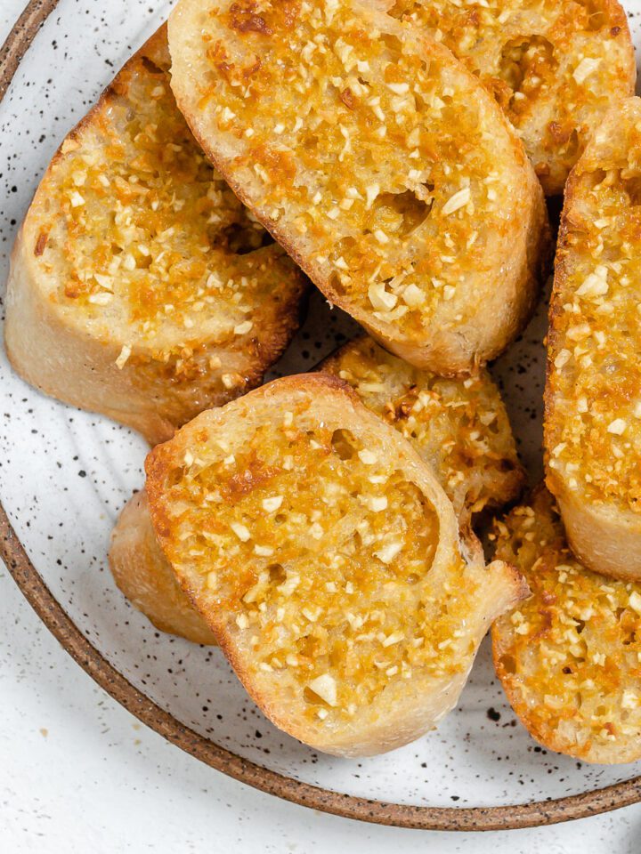 several pieces of completed Vegan Air Fryer Garlic Bread on a white plate
