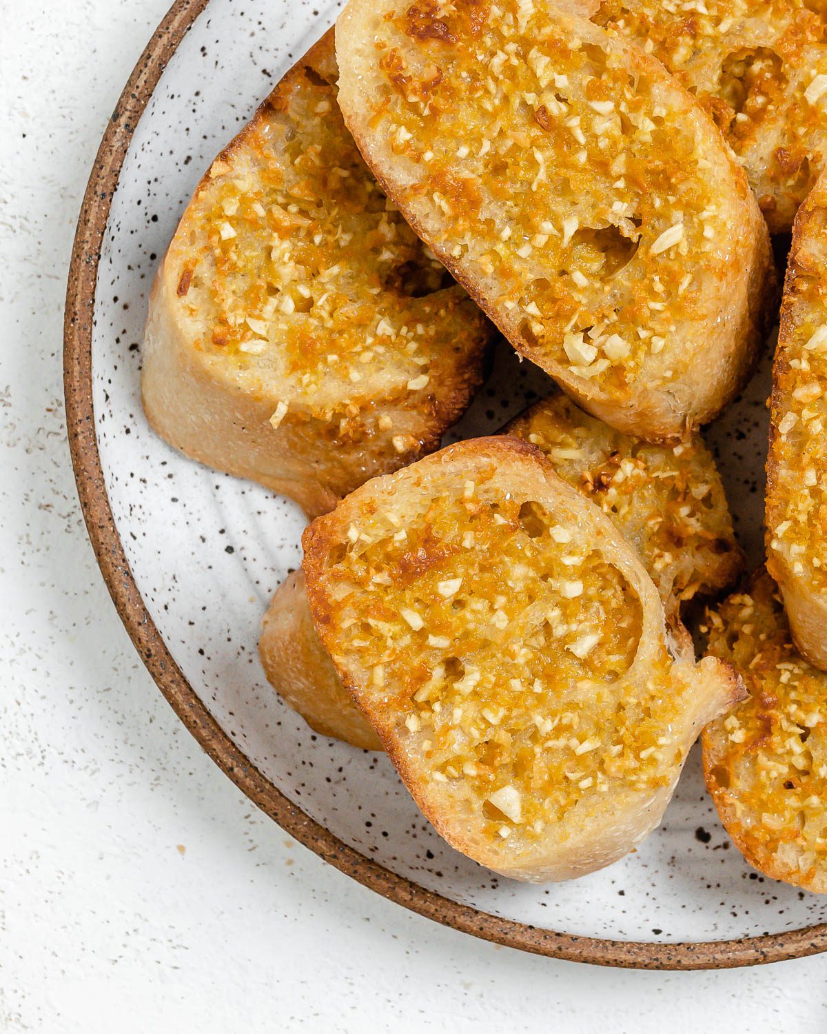 several pieces of completed Vegan Air Fryer Garlic Bread on a white plate