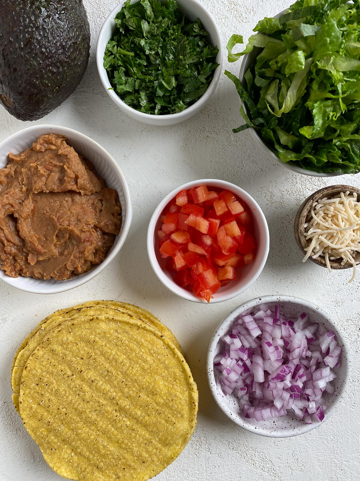 ingredients for Vegan Bean Tostadas measured out in bowls against a white background