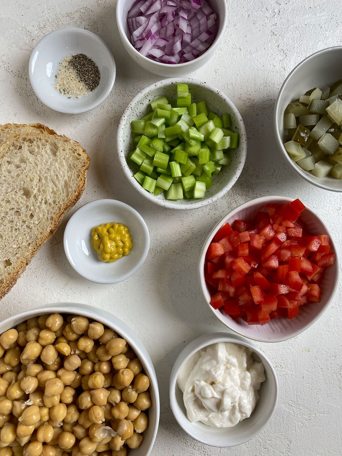 ingredients for Vegan Chickpea Salad Sandwich measured out against a white surface