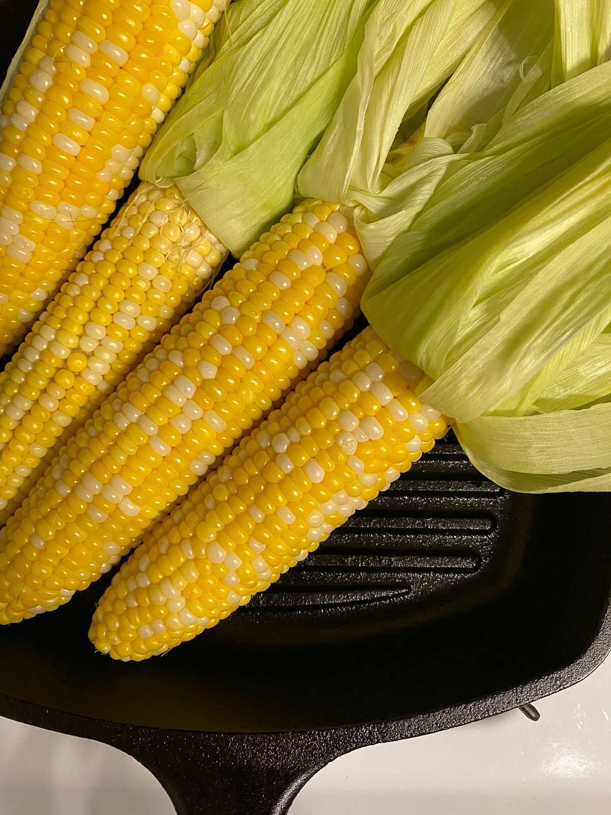 four cobs of corn on a black skilled