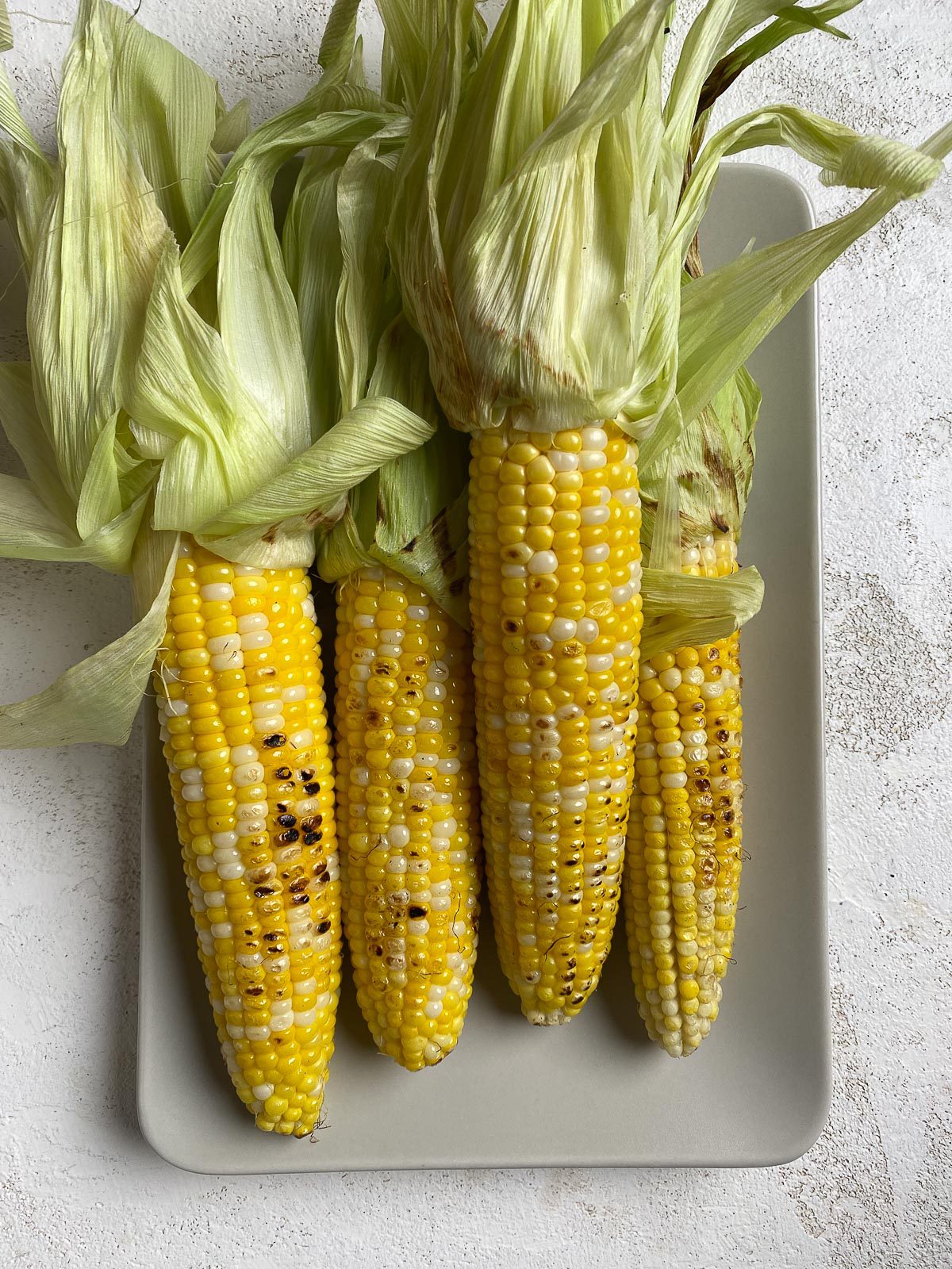 four cobs of corn on a light dish