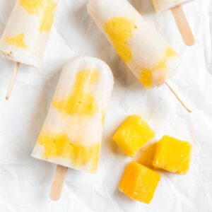several completed Vegan Mango Popsicles against a white surface