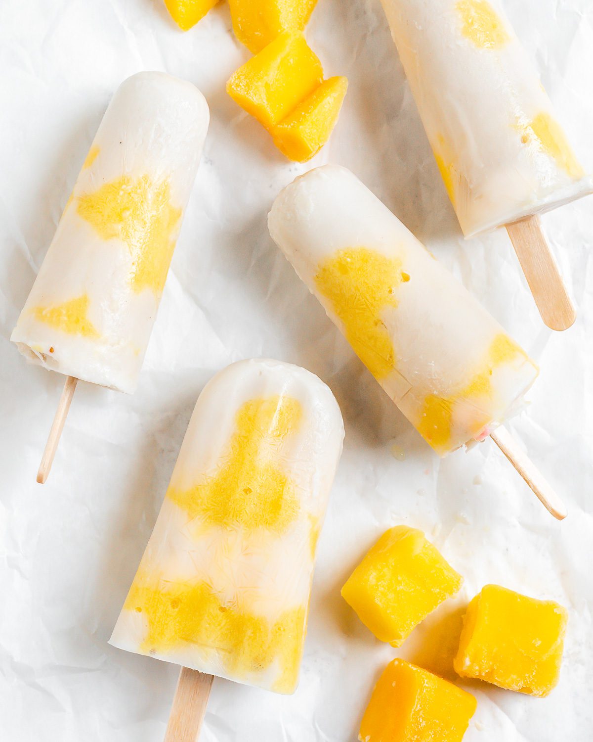 several completed Vegan Mango Popsicles against a white surface