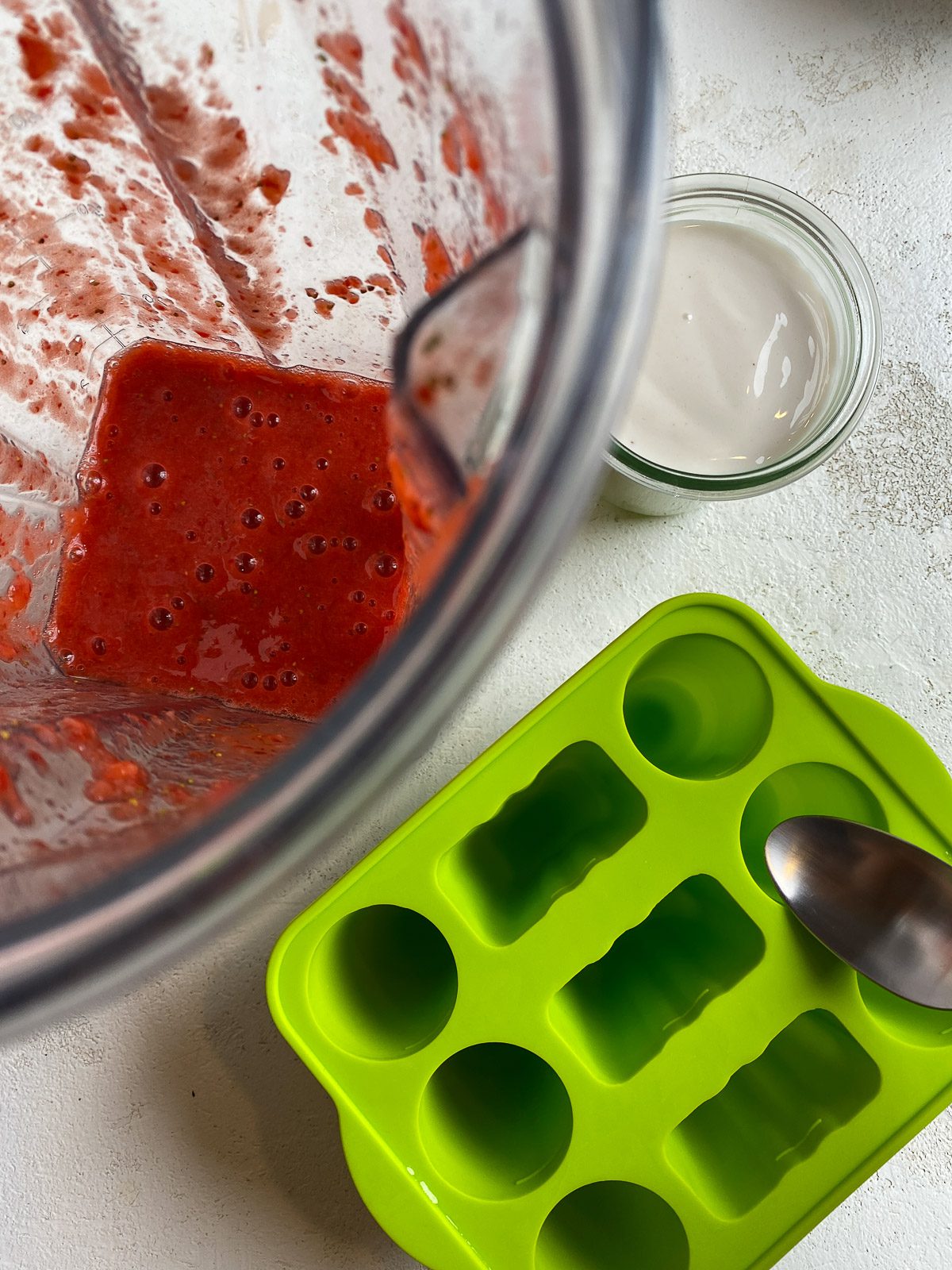 process of adding strawberry mixture to popsicle molds