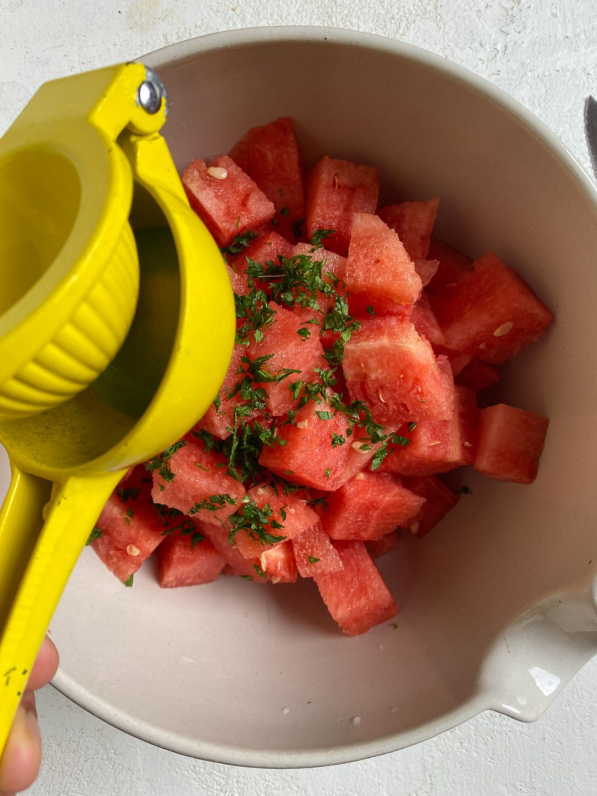 process of squeezing lime juice into bowl of watermelon