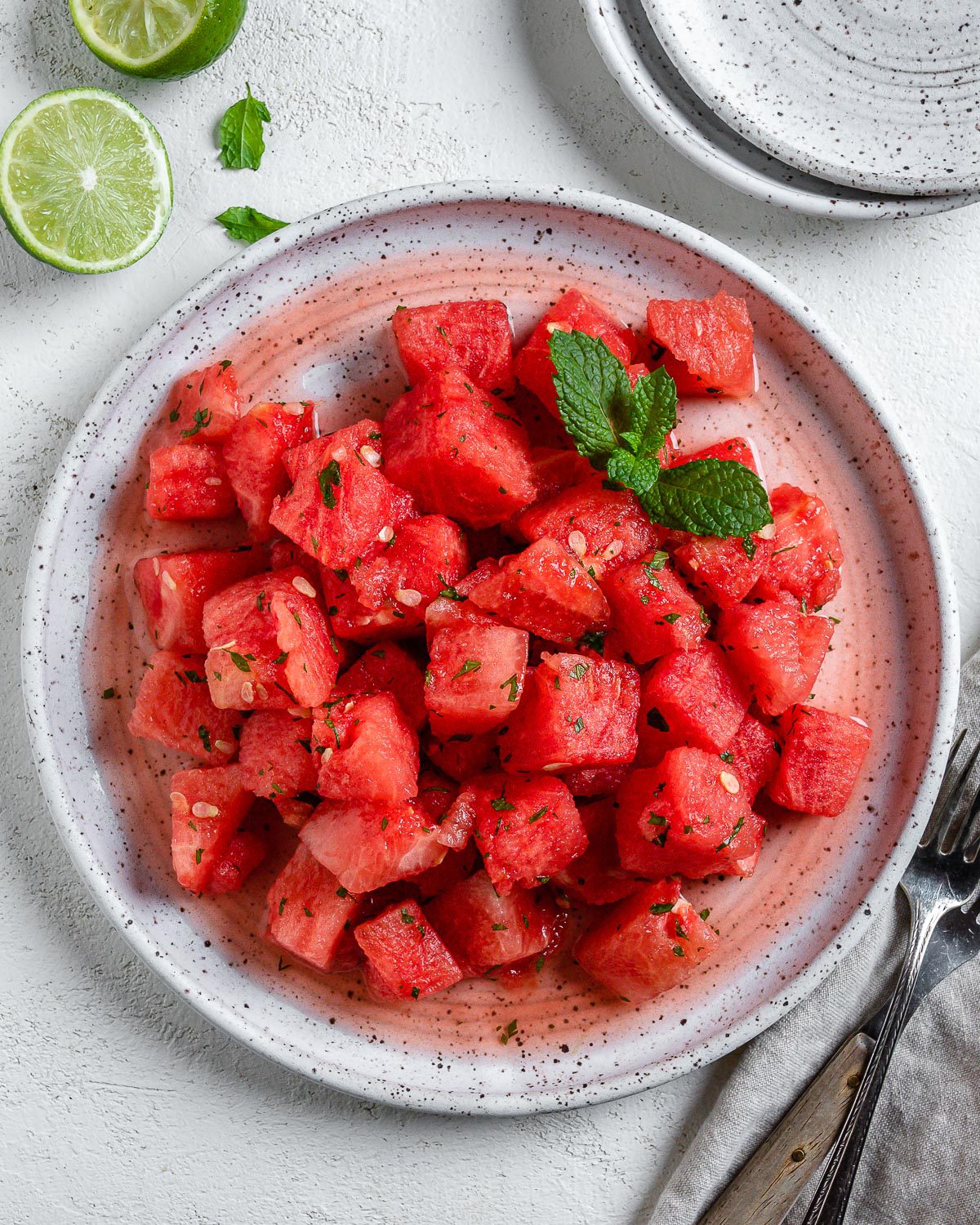 completed Vegan Watermelon Lime Mint Salad on a white plate against a white surface