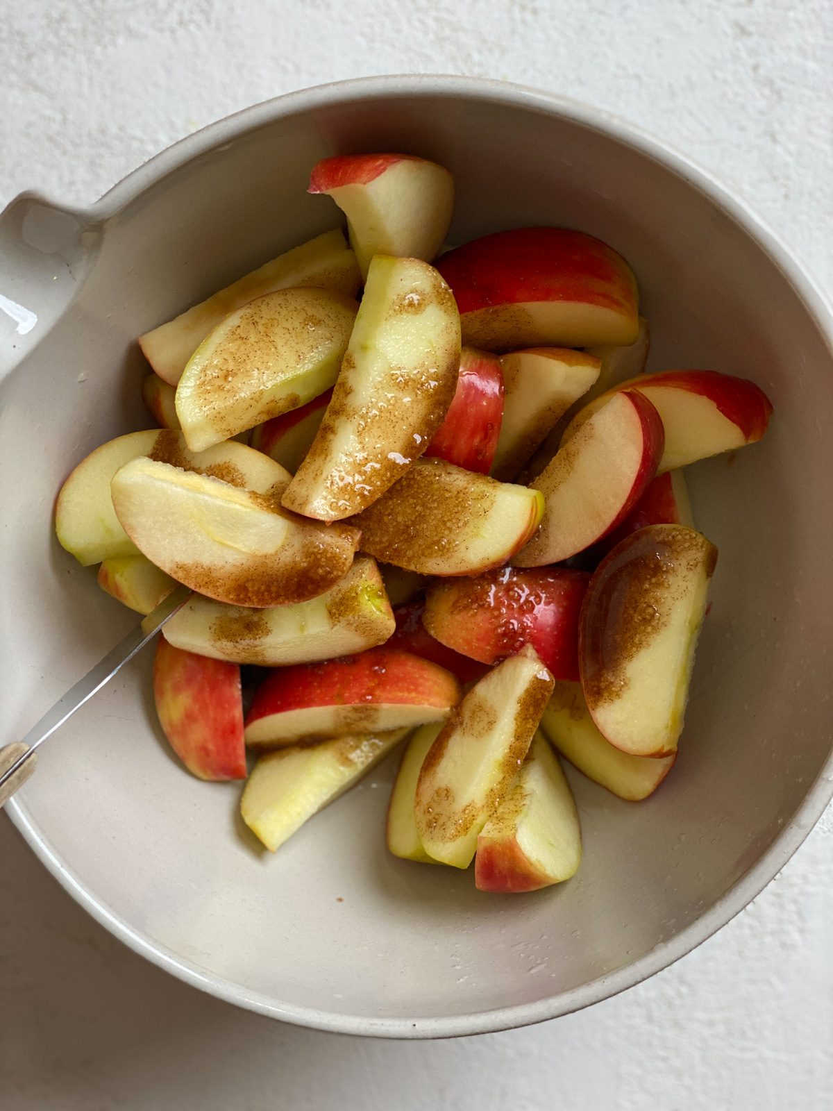 process of mixing apple topping with apples in a bowl