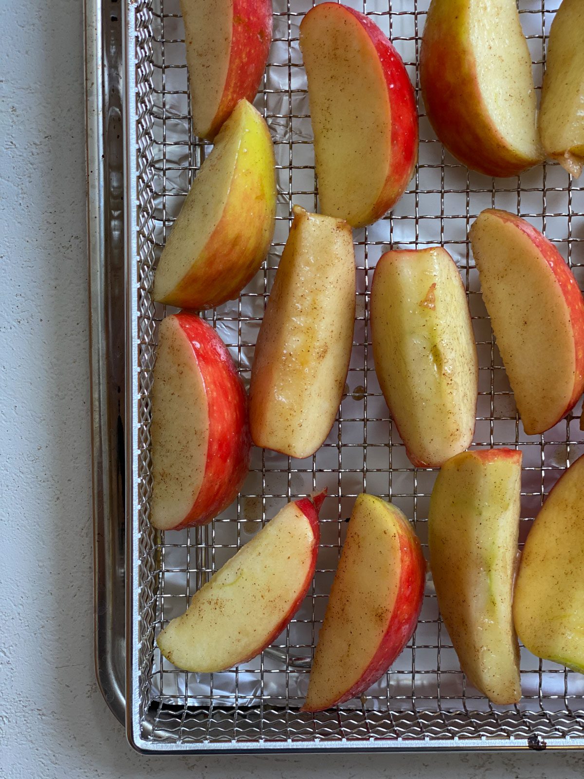 process of placing apples with topping on an air fryer wire rack