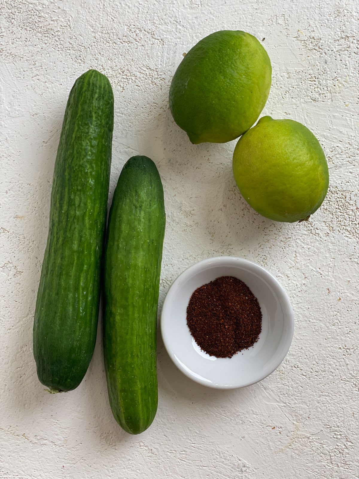 ingredients for Cucumbers with Tajin against a white surface