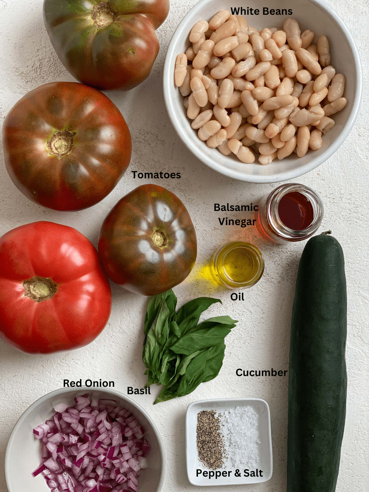 Ingredients for Easy Mediterranean White Bean Salad measured out on a white surface.