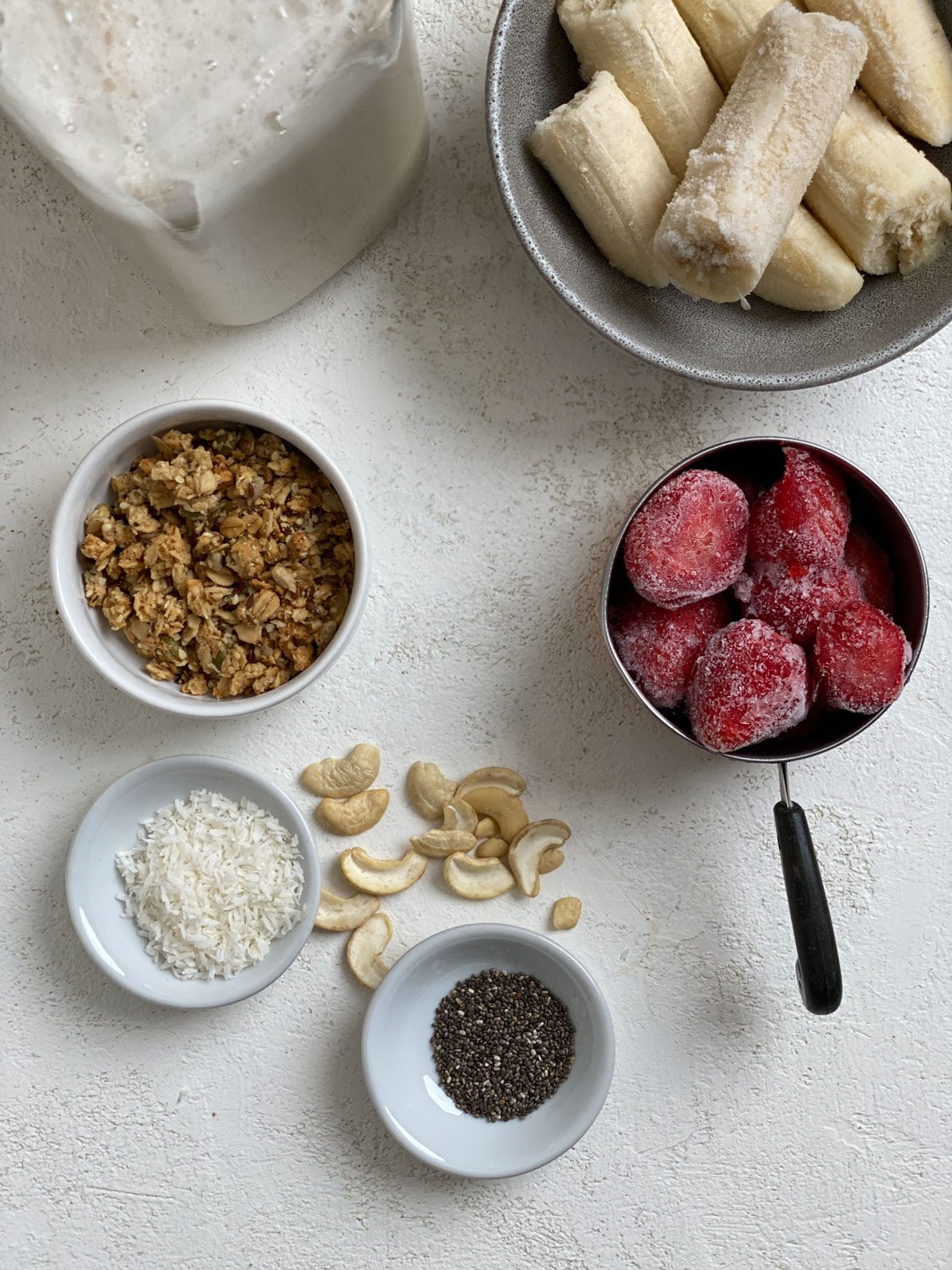ingredients for Strawberry Smoothie Bowl against a white surface