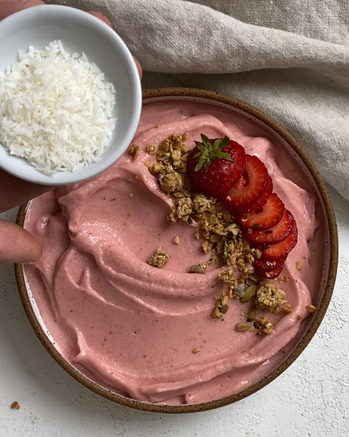 process of adding coconut topping to Strawberry Smoothie Bowl