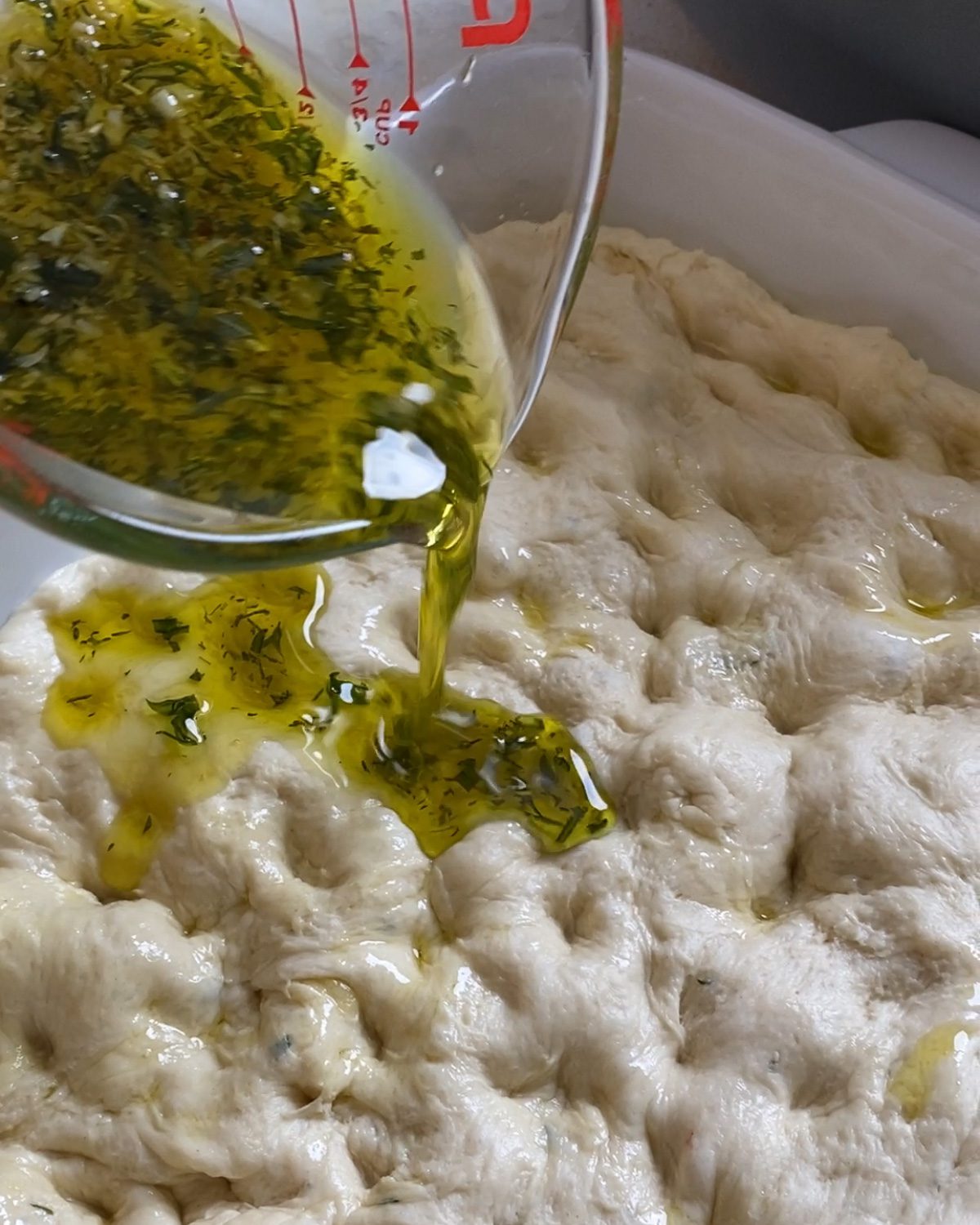 process of adding oil and herb mixture on top of dough