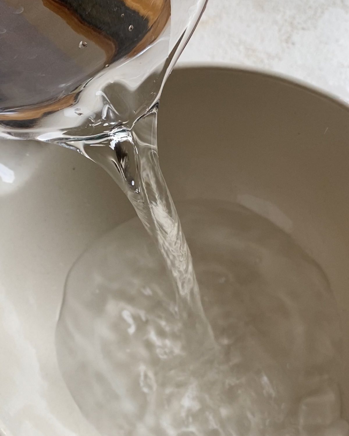 process of pouring warm water into a bowl