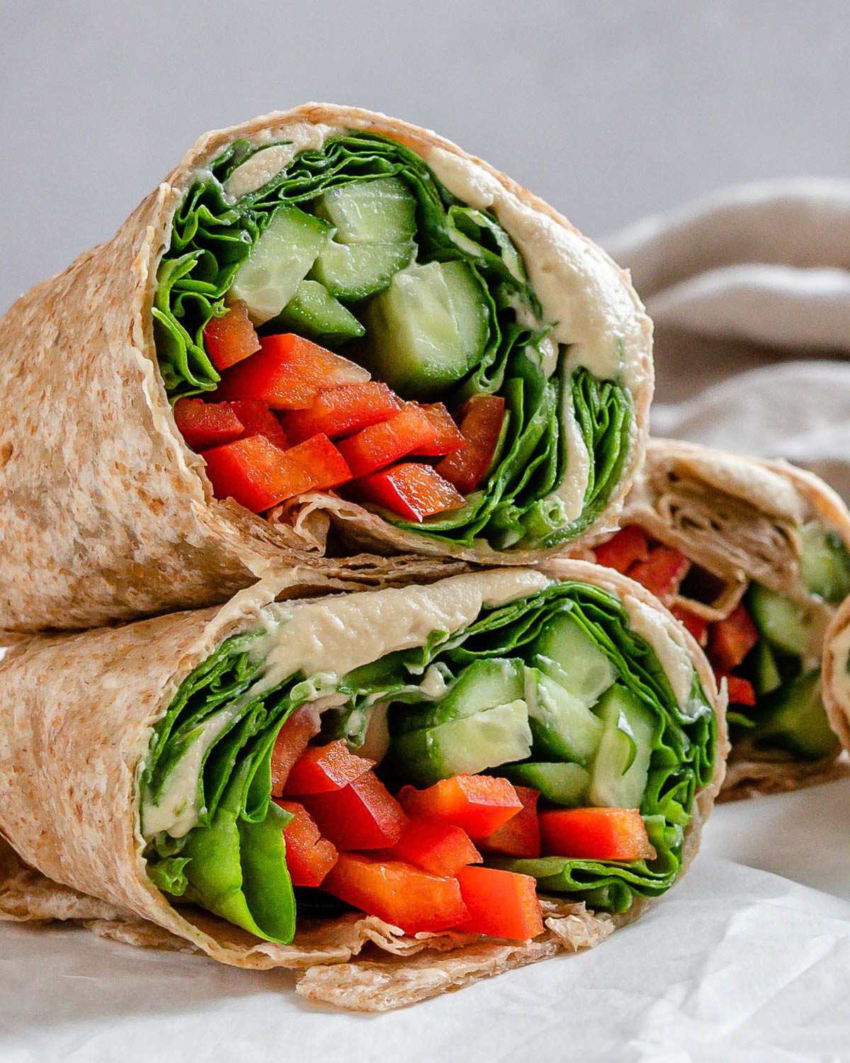 completed hummus wraps against a light surface stacked on one another