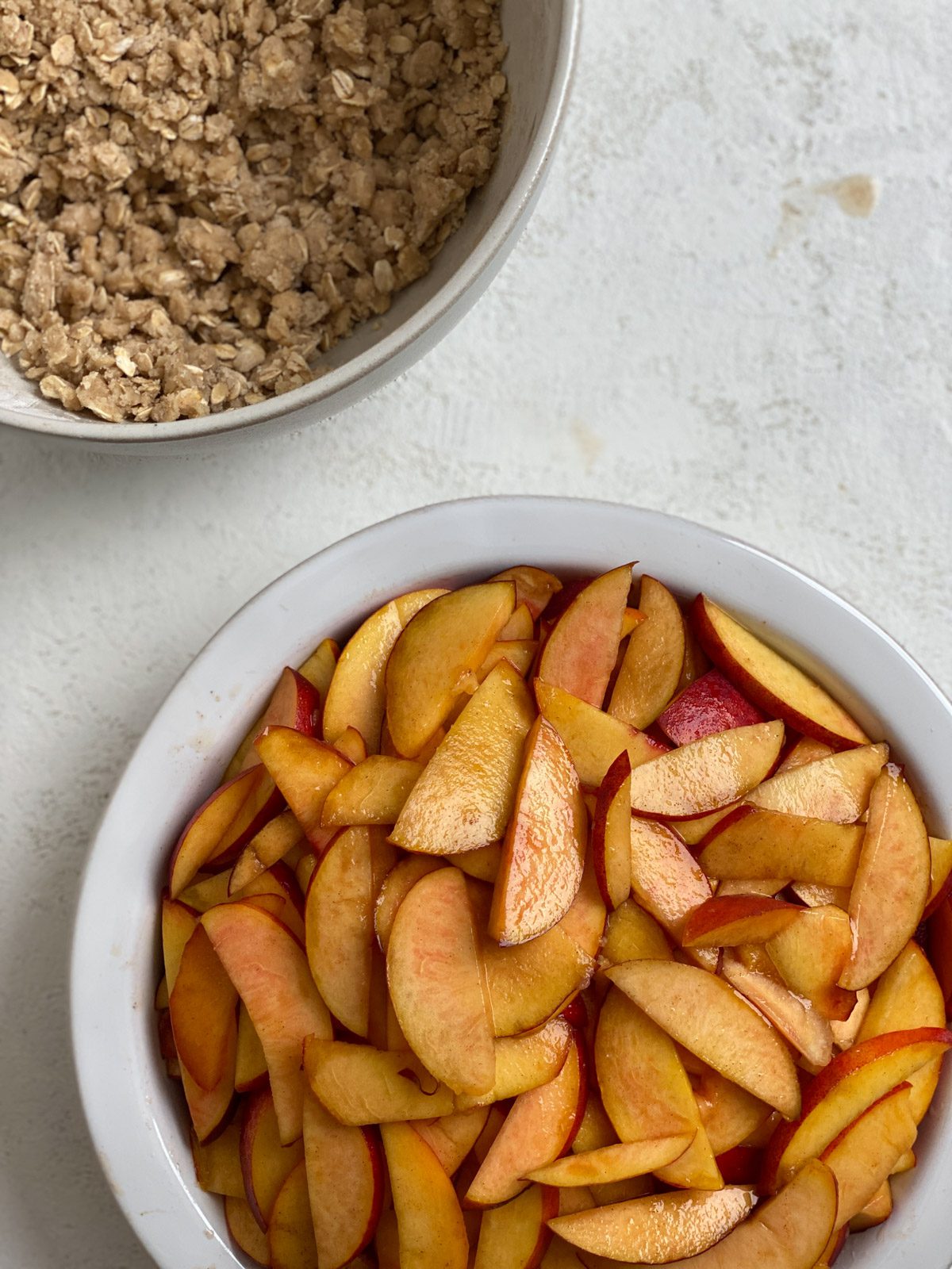 sliced peaches alongside bowl of topping ingredients