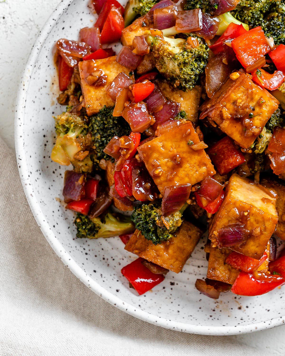 completed Vegan Teriyaki Tofu Stir Fry plated on a white bowl against a light surface