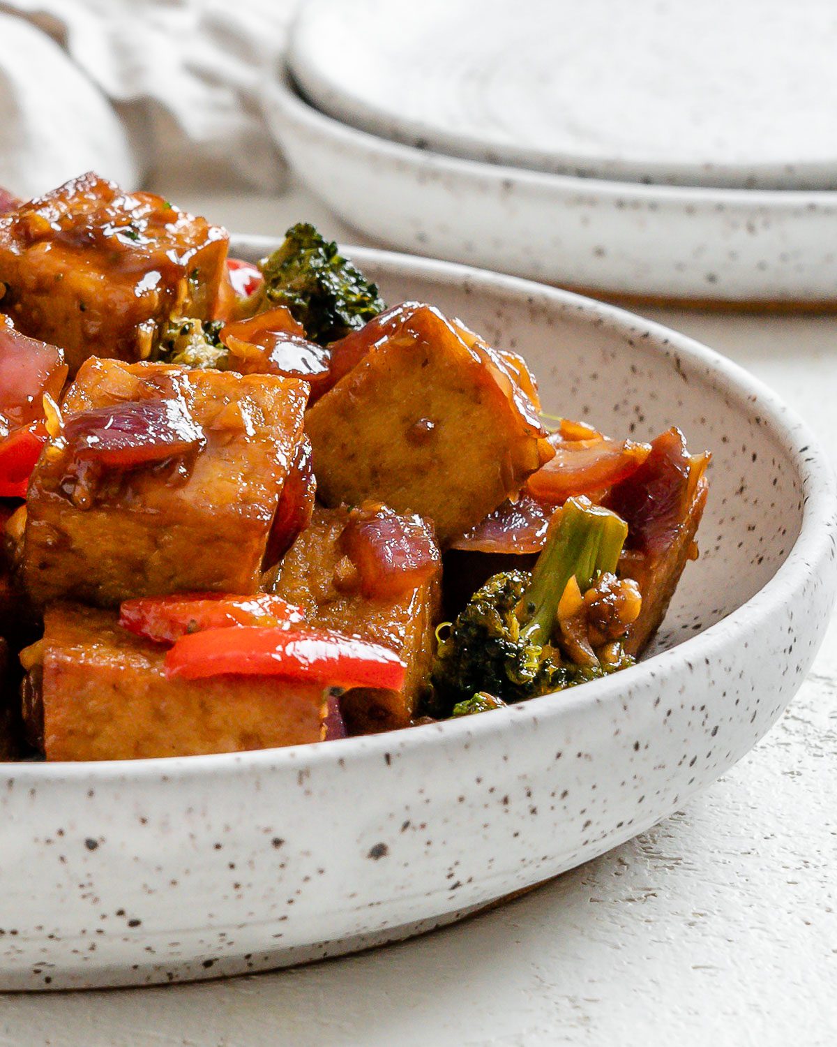 completed Vegan Teriyaki Tofu Stir Fry plated on a white bowl against a light surface