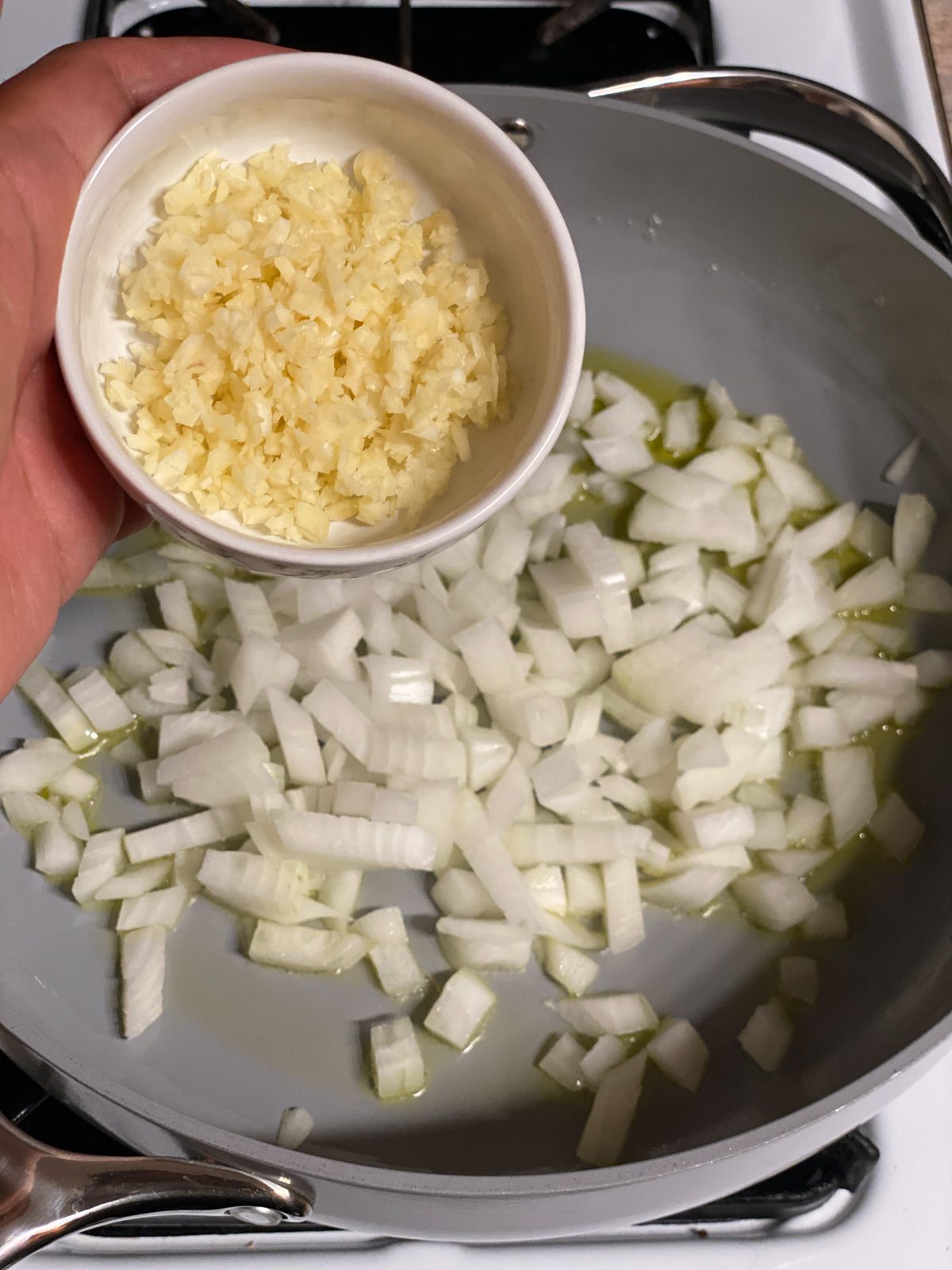 process of pouring garlic into pan