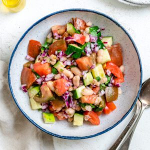 completed Easy Mediterranean White Bean Salad in a bowl alongside utensils