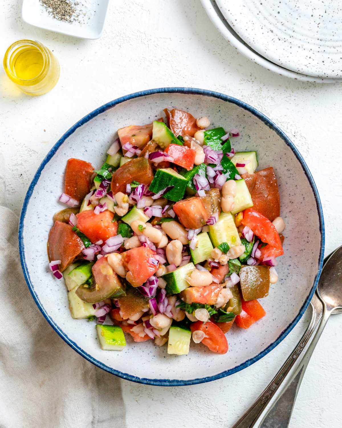 completed Easy Mediterranean White Bean Salad in a bowl alongside utensils