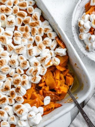 completed Vegan Candied Yams with Marshmallows in a baking dish against a white background