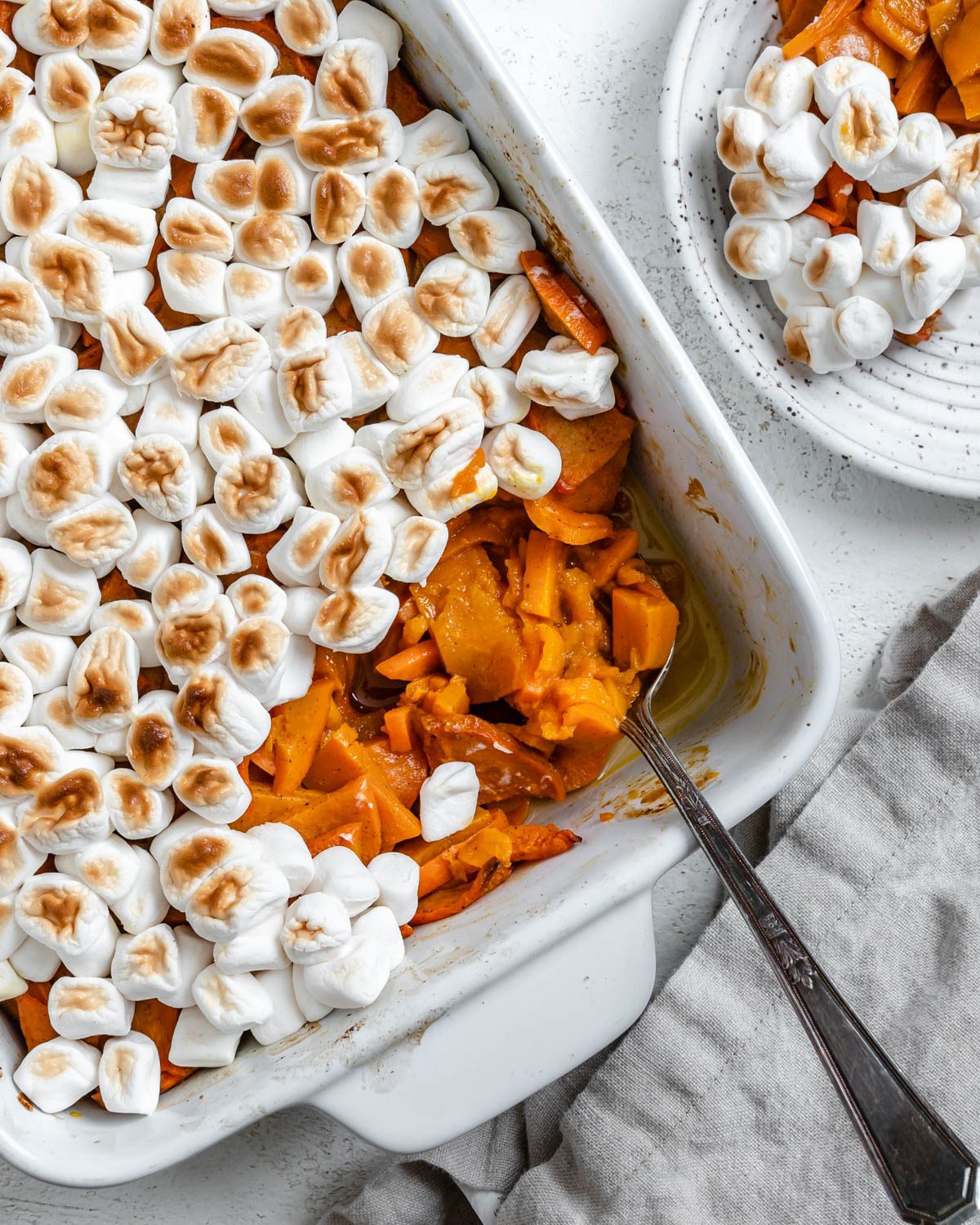 completed Vegan Candied Yams with Marshmallows in a baking dish against a white background