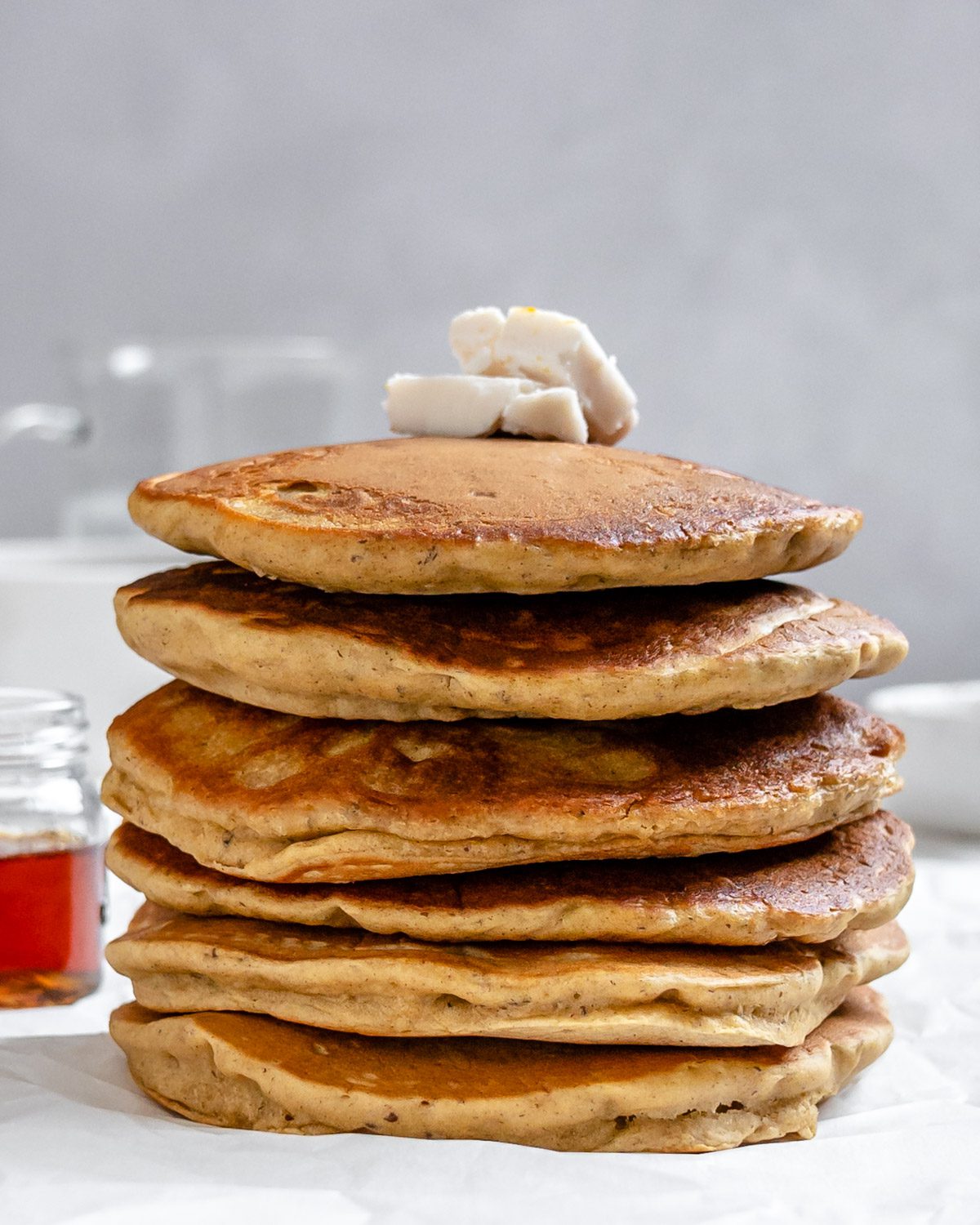 completed stack of Vegan Pumpkin Pancakes against a white background with vegan butter on top