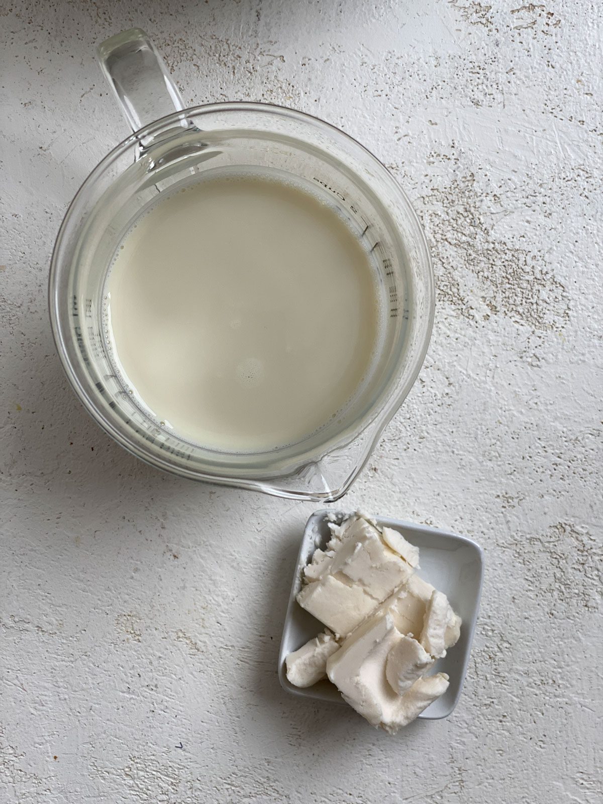cup of plant-based milk alongside plant butter against a white surface