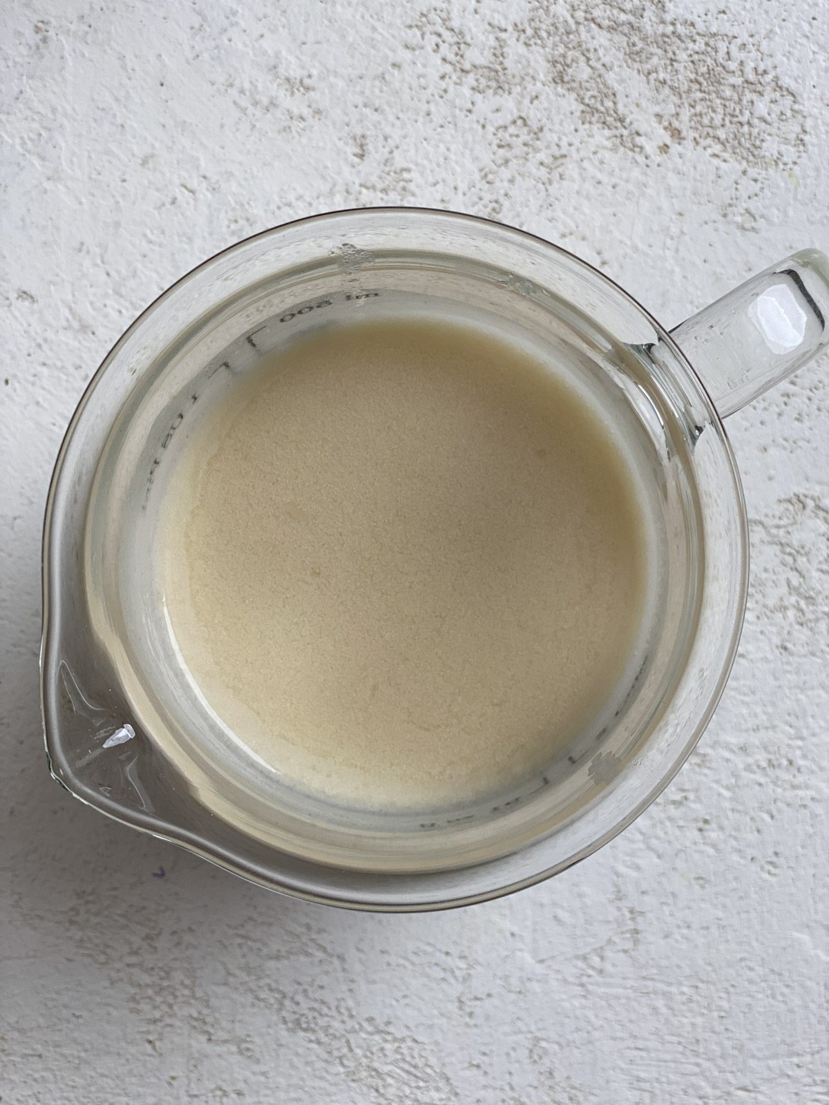 post microwaved plant butter and milk in a glass cup against a white surface