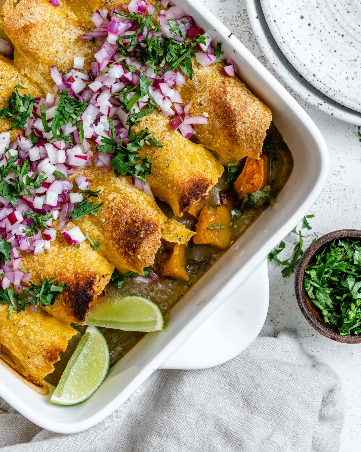 completed Easy Butternut Squash Enchiladas in a baking tray against a white background