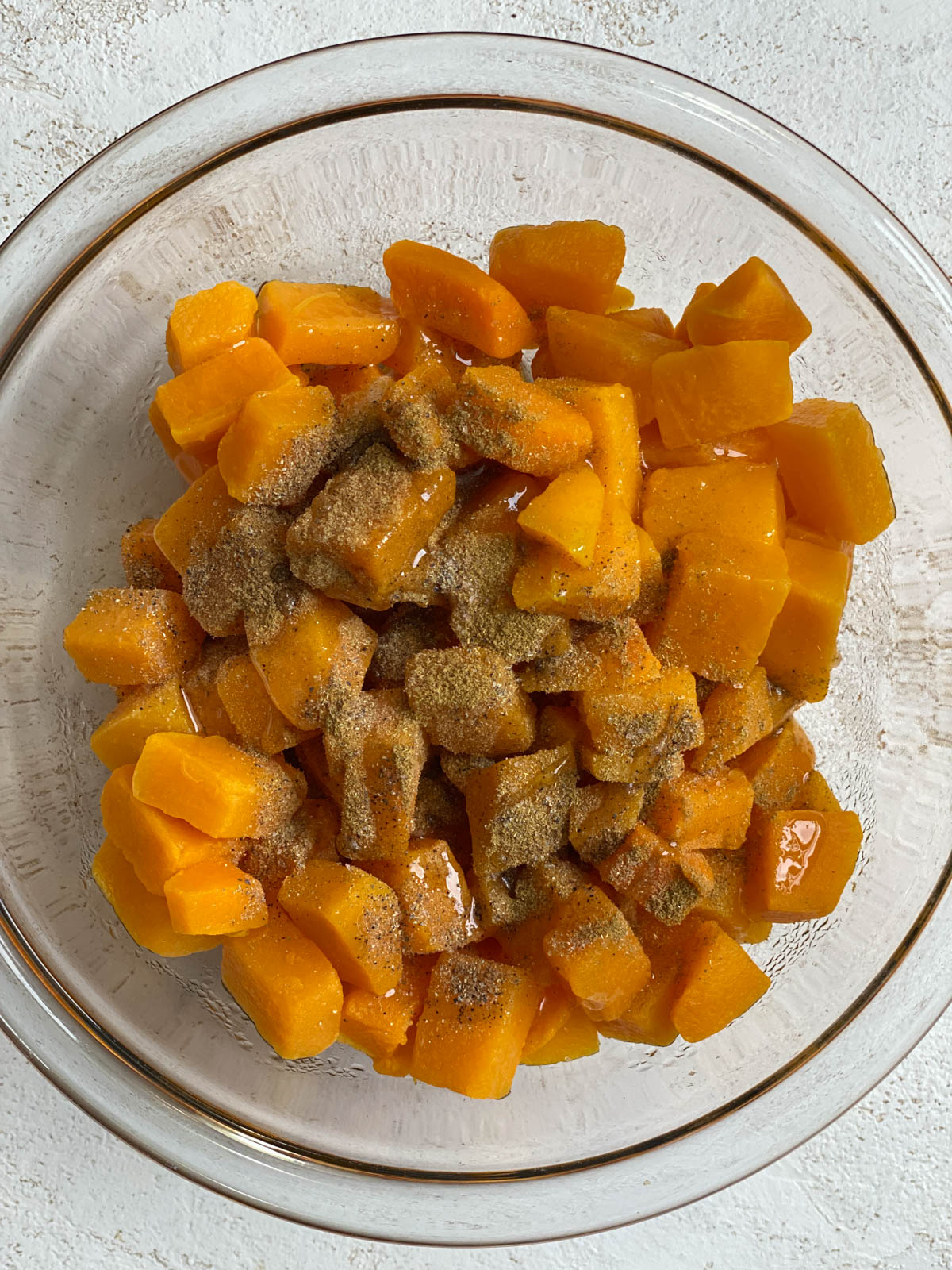 butternut squash and spice in a clear bowl against a white background