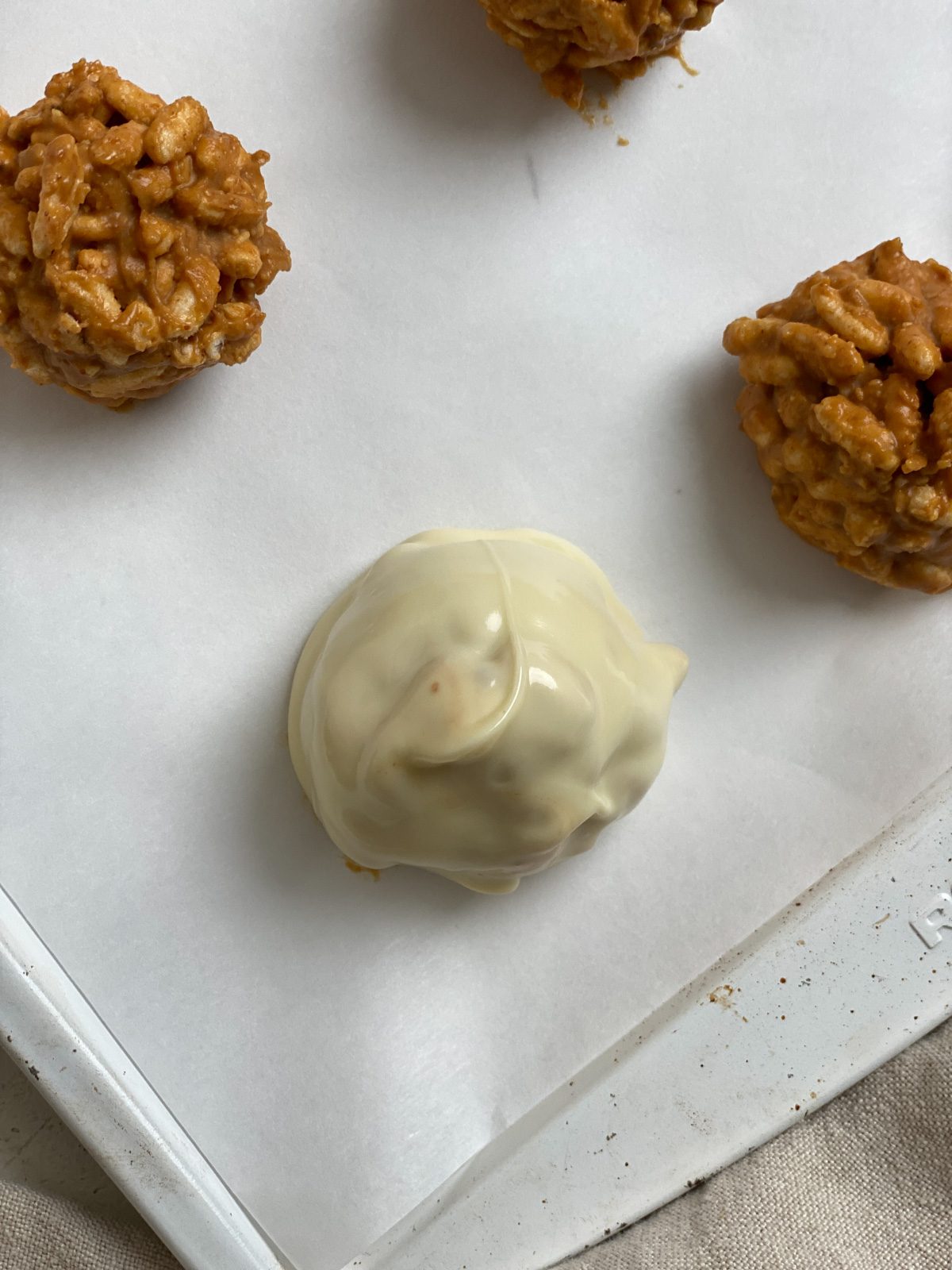 close up shot of dipped peanut butter ball alongside non-dipped balls