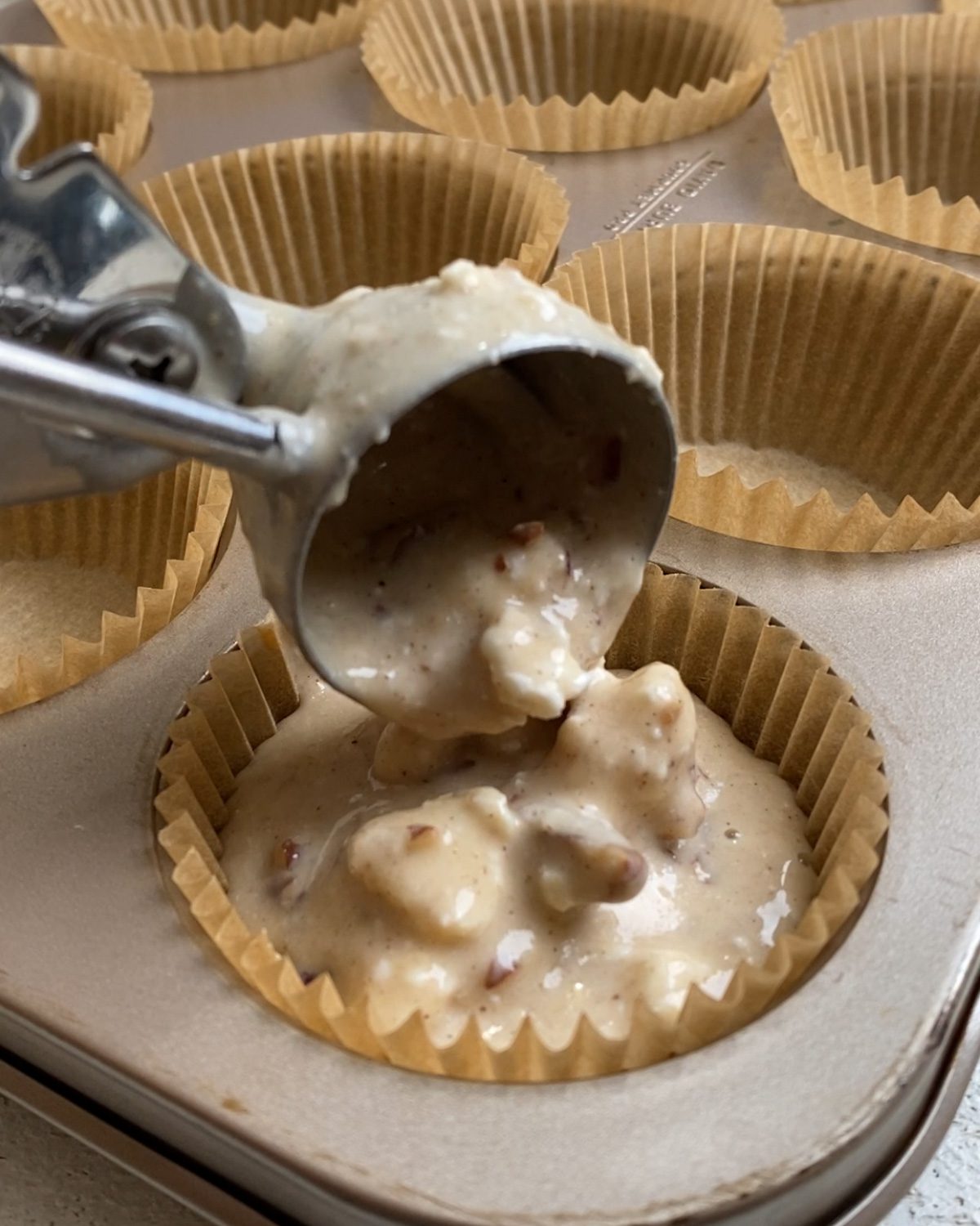 process shot of adding muffin batter to muffin tin