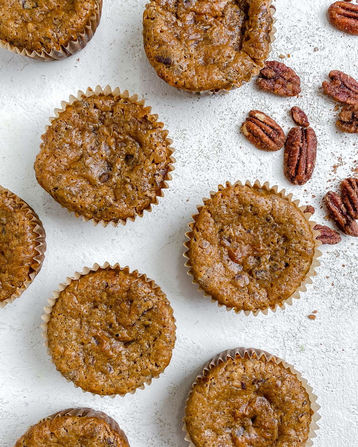completed Vegan Cinnamon and Banana Pecan Muffins scattered on a white surface