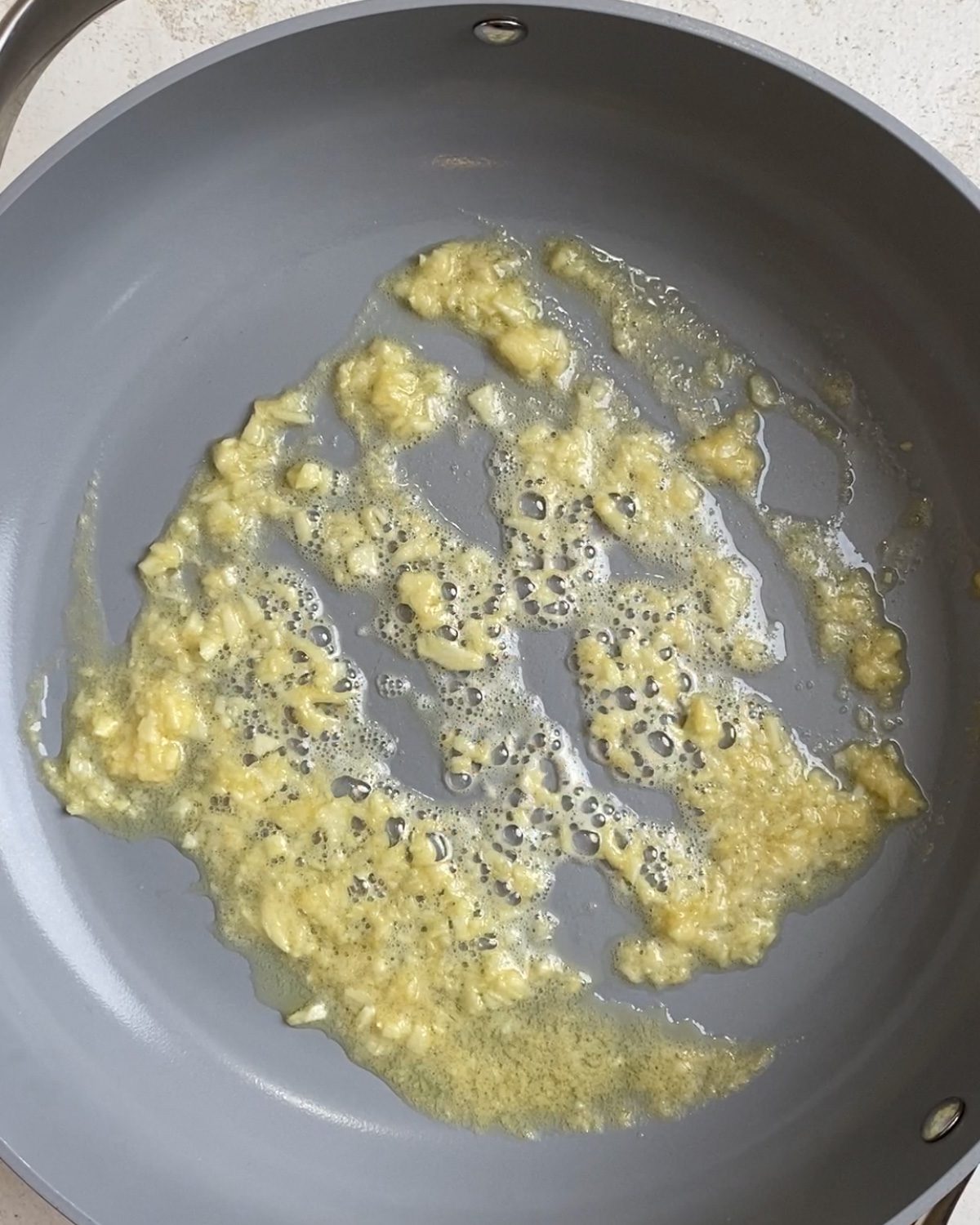 process shot of butter and garlic cooking on a pan
