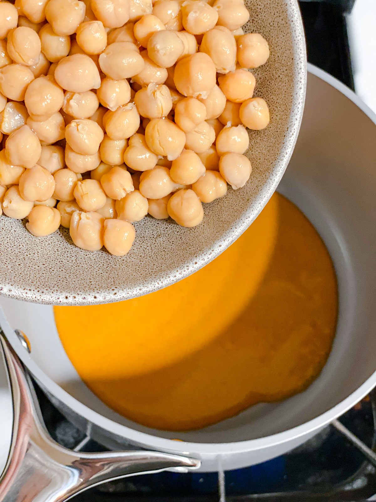 process of adding chickpeas to bowl