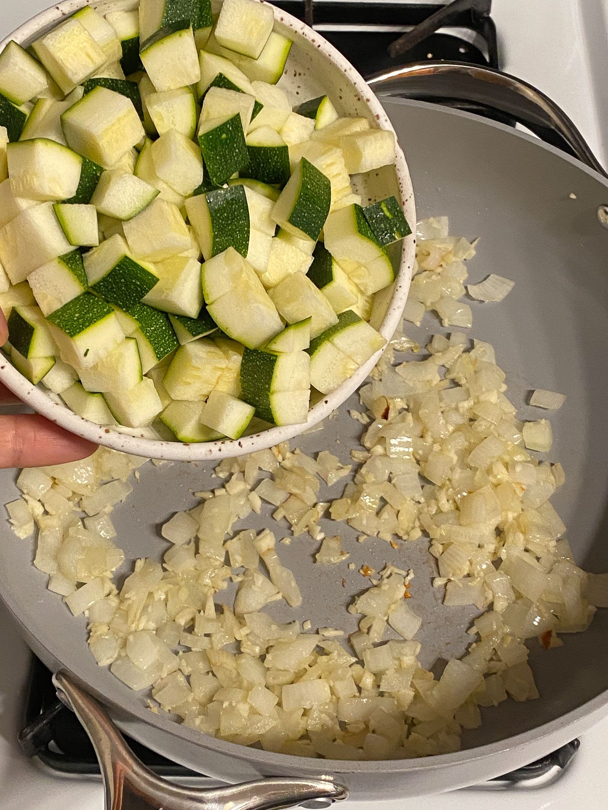 process shot of adding zucchini to pan
