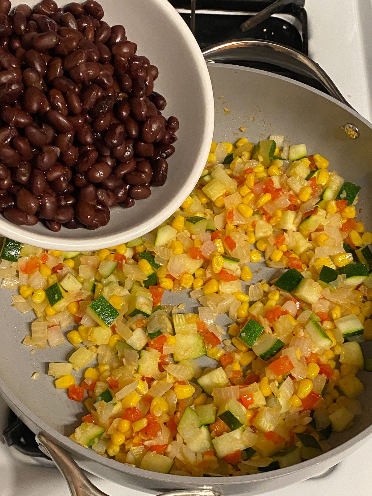 process shot of adding black beans to pan