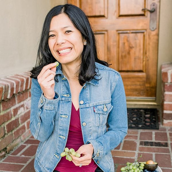 Photo of Toni Okamoto, the author of this website, eating grapes and sitting on a porch.